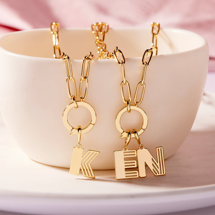 Gold necklaces with letter pendants on a white dish