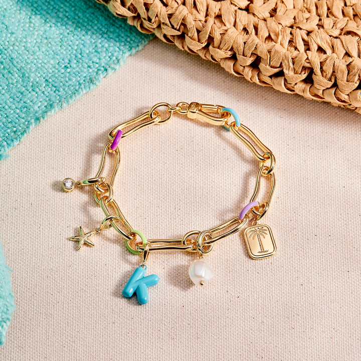 Gold bracelet with various charms on a textured surface
