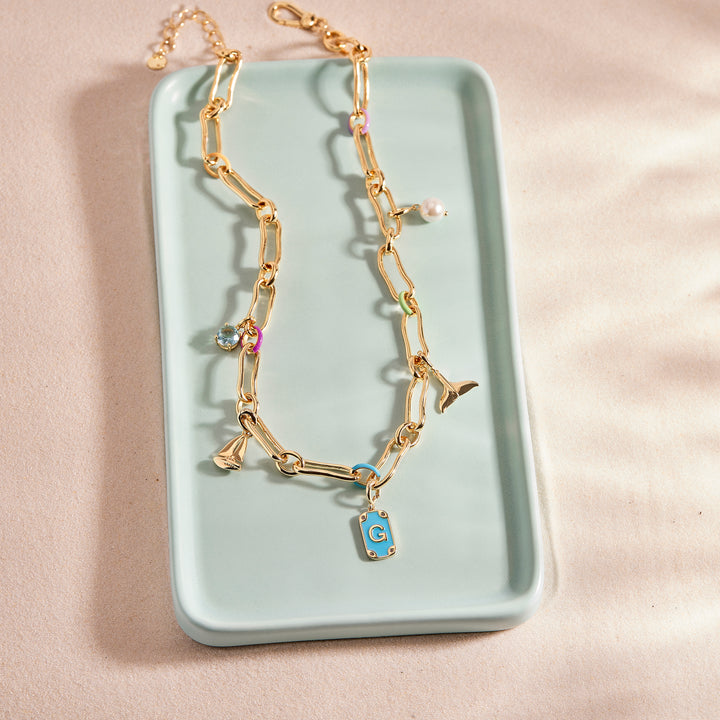 Gold necklace with a blue pendant on a light green tray