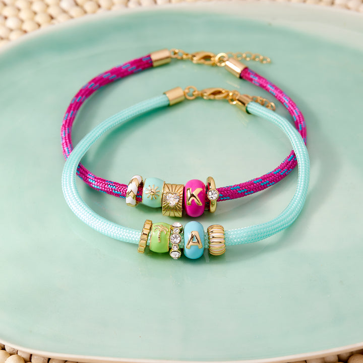 Two colorful bracelets with beads on a light green plate