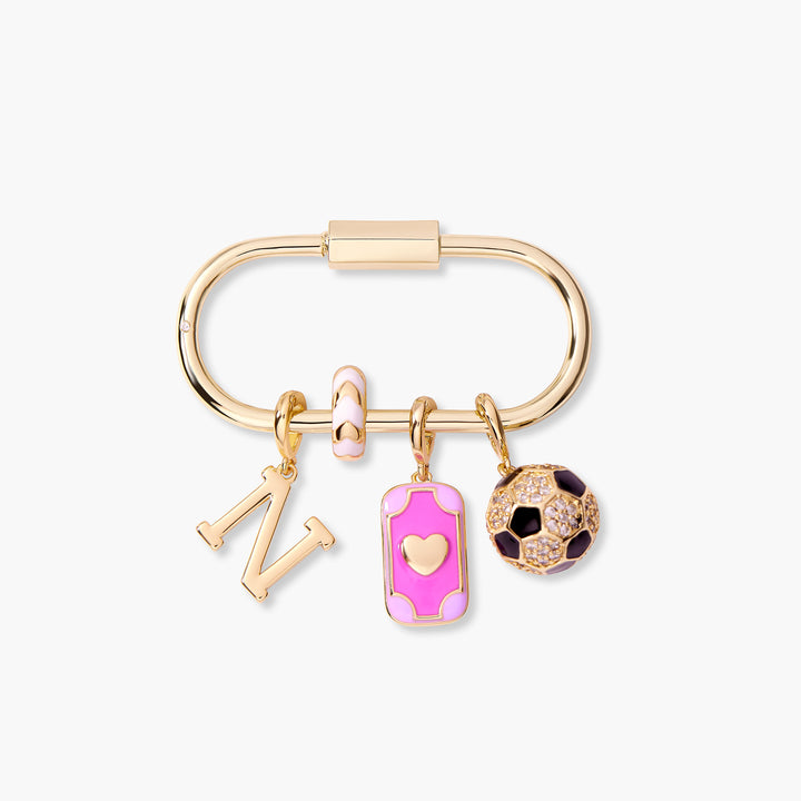 Oval carabiner key chain with an initial letter charm, pink enamel rectangular heart charm, and a pavé soccer ball charm.