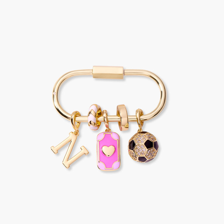 Oval carabiner key chain with an initial letter charm, pink enamel heart tag charm, and pavé soccer ball charm with black enamel panels.