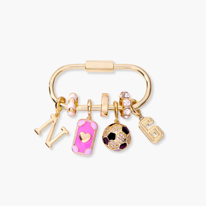 Charm key chain with a carabiner clasp, an initial letter, pink enamel rectangular heart charm, crystal soccer ball charm, and a number charm.