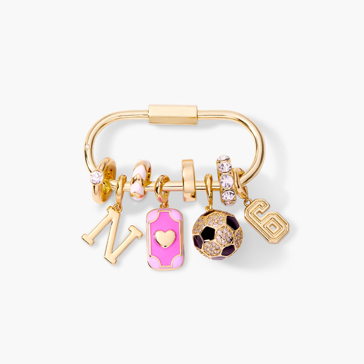 Gold-tone carabiner bag charm key chain with a block-letter initial, pink enamel rectangular charm, crystal soccer ball charm, and a number charm.