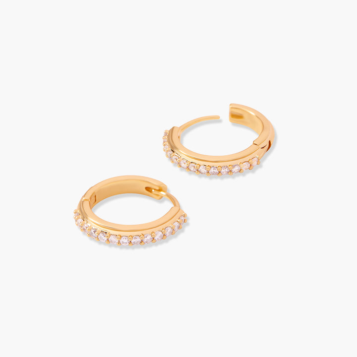  Pair of huggie hoop earrings with pink crystal pavé set along the outer edge, angled side view.