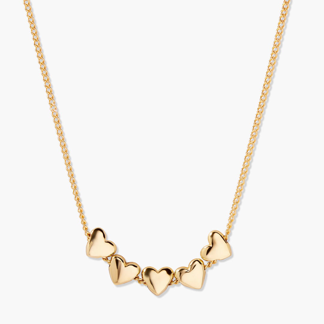 Posy Heart Necklace with five polished puffy hearts linked along a gold-tone chain.