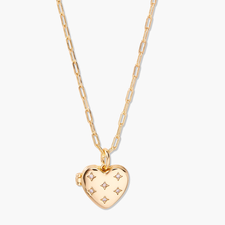Gold-tone heart locket necklace on a chain, with a puffy quilted surface accented by five four-pointed crystal star motifs.
