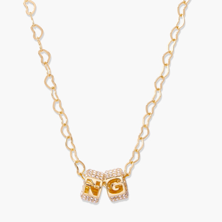 Initial letter cube charm necklace with two pavé crystal-encrusted cubic beads threaded on a heart-link chain.