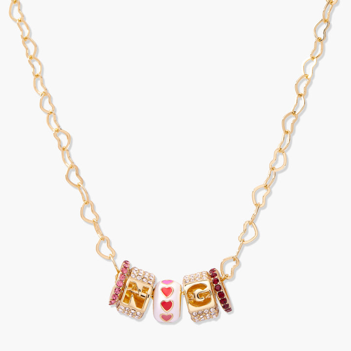 Gold-tone heart-link chain necklace with customizable initial letter charms and a heart enamel bead accent, trimmed with pink crystal spacers.
