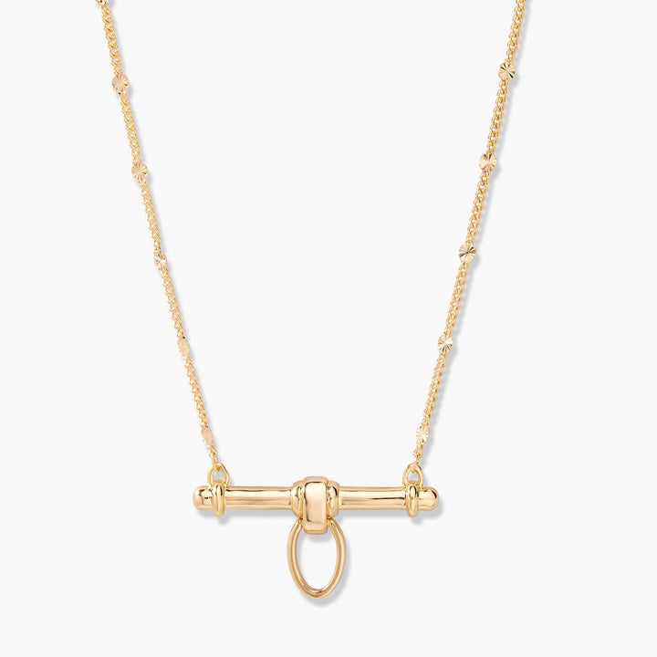 Gold-tone Poppy Bar Charm Necklace with a polished cylindrical bar pendant, knotted center loop, and flat disc-accented chain.