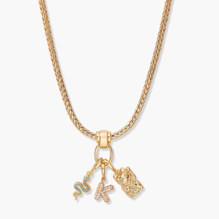 Charm necklace with a braided chain, ring clasp, and three dangling charms: a pavé initial, a snake, and a lucky cat figurine.