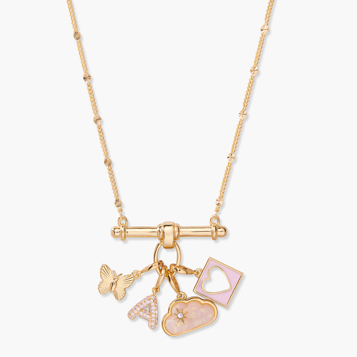 Gold-tone charm bar necklace with four dangling charms: a butterfly, a pavé initial letter, a pink opal cloud, and a rectangular pink enamel heart cutout pendant.