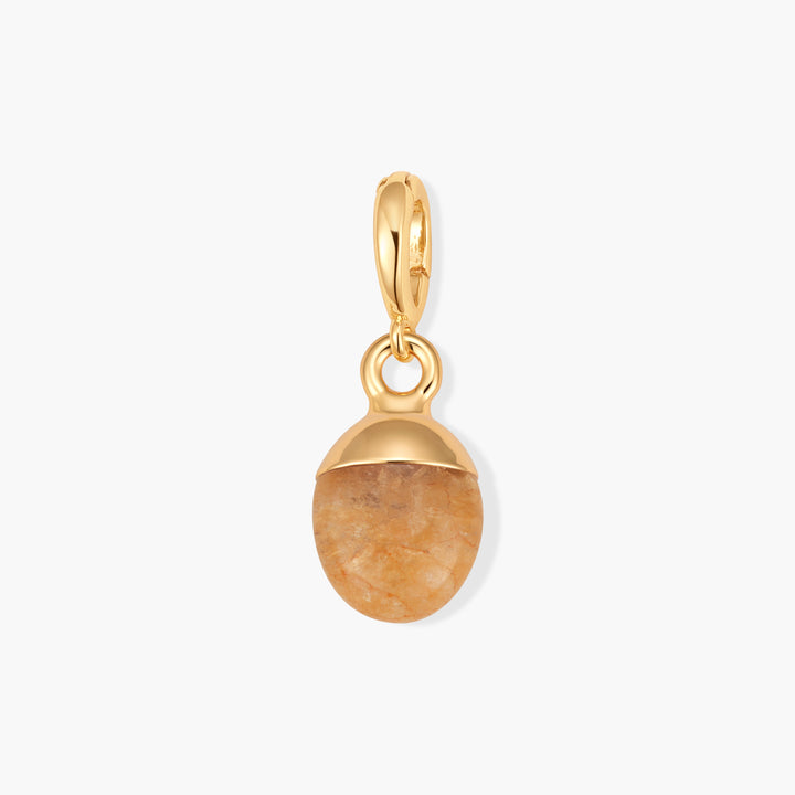 Perla Birthstone Charm with an oval peach citrine stone capped by a domed setting and a ring clasp.