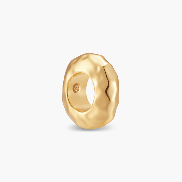 Gold-tone Gaby Hammered Bead charm with a chunky, organically sculpted surface and a small stone set inside the band.