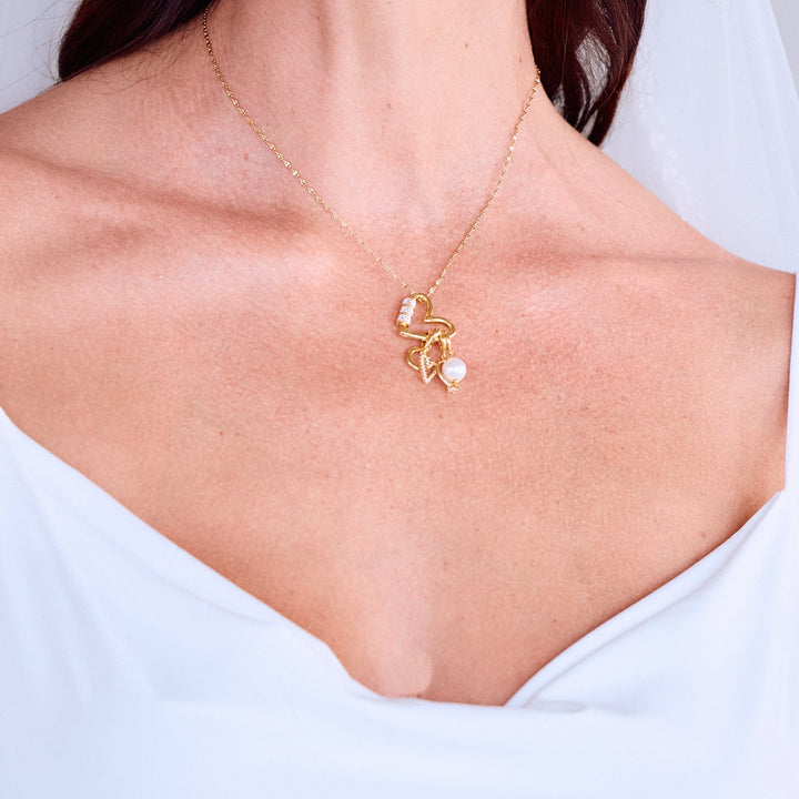 Mrs. Carabiner Charm Necklace resting on a models chest with a heart carabiner clasp, pavé heart, letter initial, ring, and pearl charms.