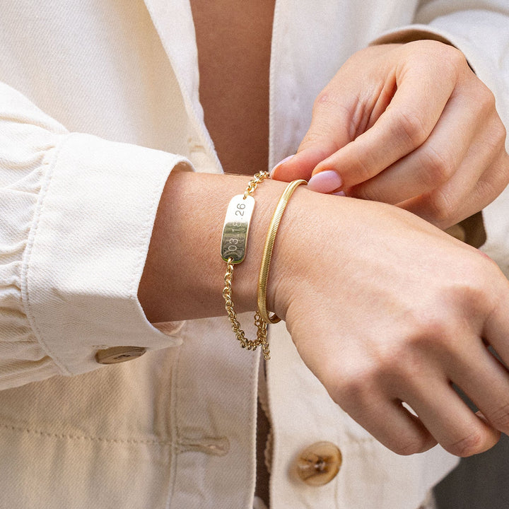 Person wearing a white blouse with rolled-up sleeves and gold bracelets.