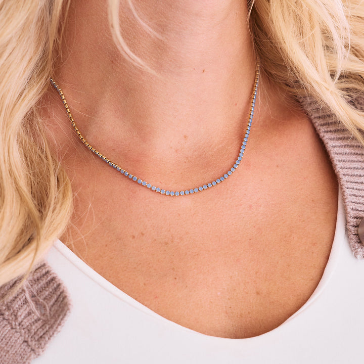 gold necklace with blue opal stones on neck.