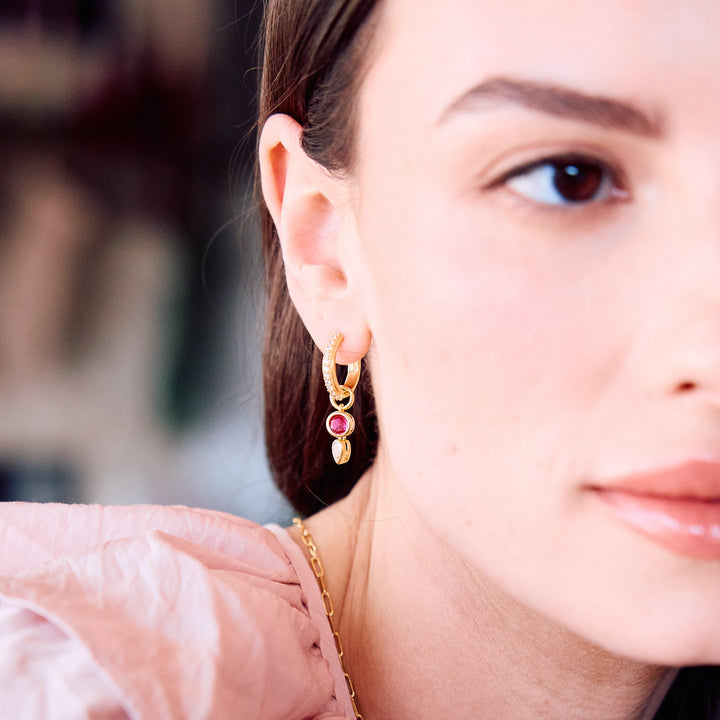  Birthstone huggie hoop earrings on a models ear.