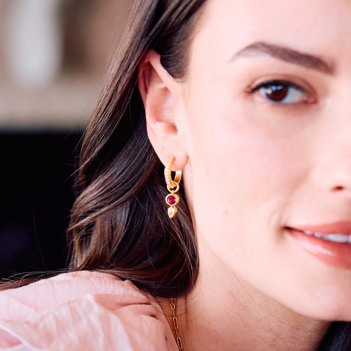Birthstone huggie hoop earrings on a models ear.