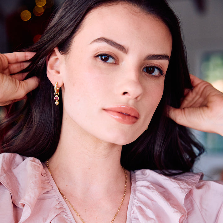 Birthstone huggie hoop earrings on a models ear.