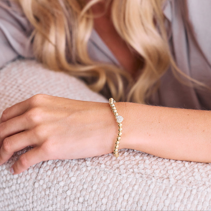 gold beaded bracelet with cz heart on arm.