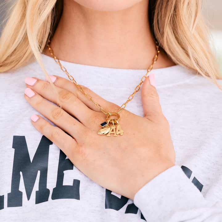 gold charm necklace with sports charms hanging.