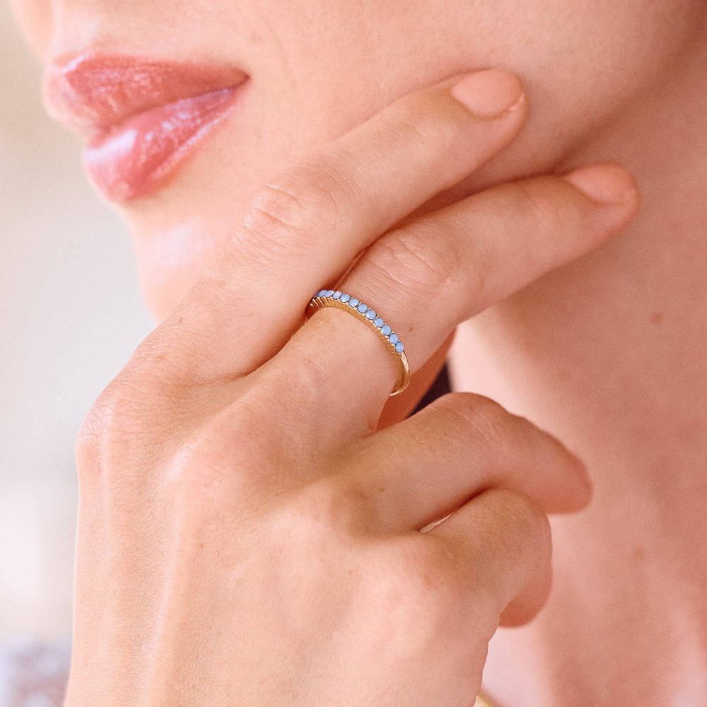  Kara Opal Thin Ring, a slim eternity-style band set with a row of round lavender opal stones in a prong setting on a models finger.