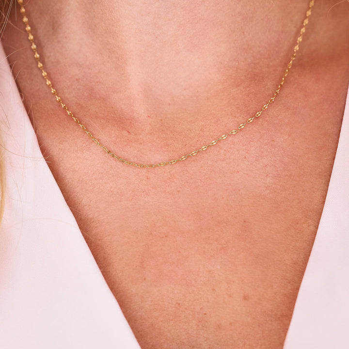 gold mirror chain on neck with pink shirt.