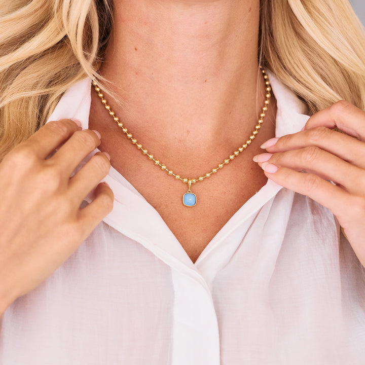 gold beaded chain necklace with blue opal charm.