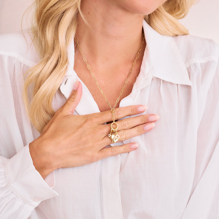 gold paperclip chain lariat necklace with heart charm hanging.