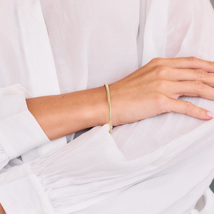 A gold-plated snake chain bracelet displayed on a women&