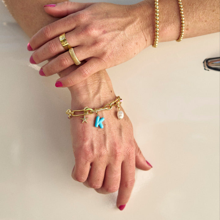 Close-up of hands wearing gold jewelry with a neutral background