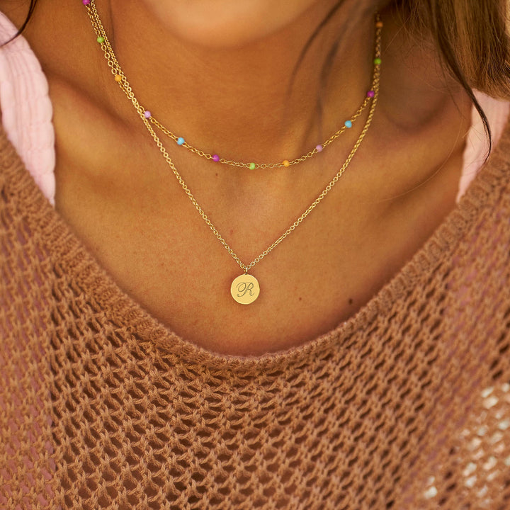 Woman wearing sunglasses and layered necklaces with a blurred background