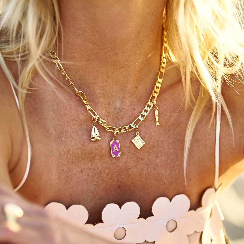  Close-up of a person wearing a gold necklace with charms, blurred background